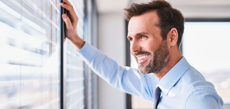 Homepage call to action thumbnail picture of a businessman feeling relieved staring outside the window