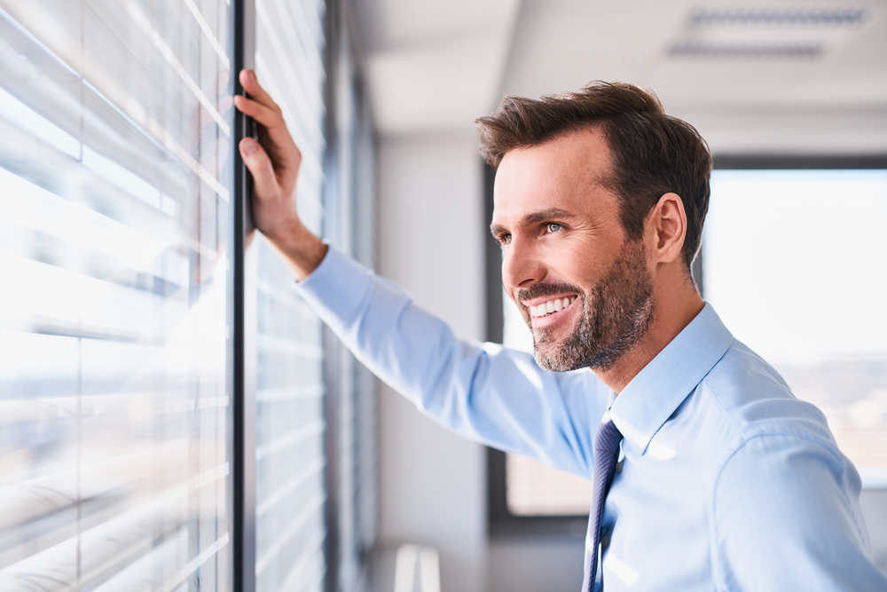 Homepage call to action thumbnail picture of a businessman feeling relieved staring outside the window